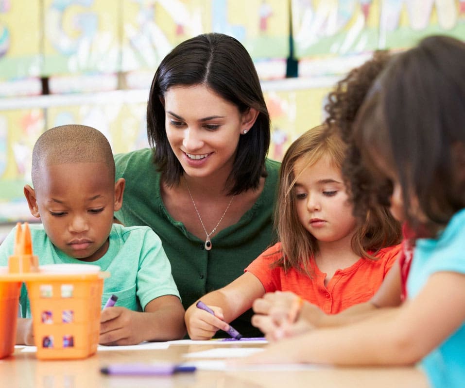 A woman is helping children with their homework.