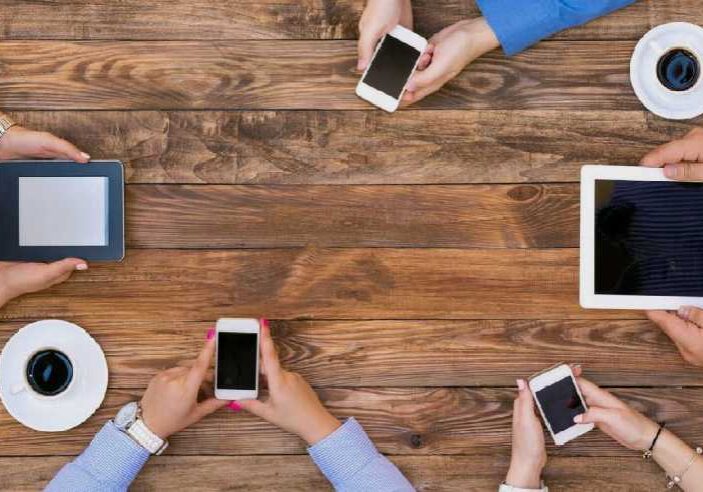 A group of people sitting at a table with their phones.