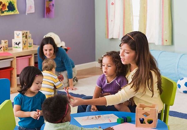 A woman is helping children with crafts.