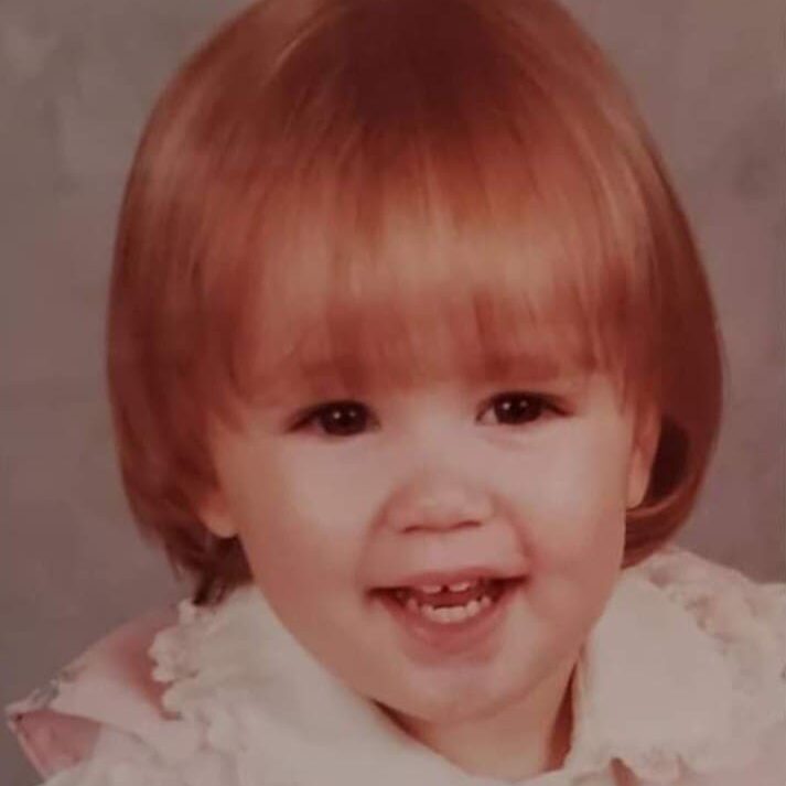 A young girl with red hair and white shirt.